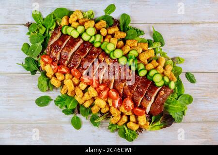 Tranches de filet de porc au barbecue servi avec une salade verte et des tomates. Banque D'Images