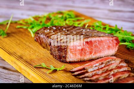 Steak de bœuf angus rare grillé en tranches sur une planche de bois. Gros plan. Banque D'Images