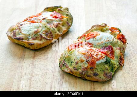 Tomates séchées et focaccia au fromage de chèvre sur une planche à découper en bois Banque D'Images