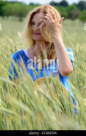 femme d'âge moyen avec livre un chapeau de paille appréciant la vie Banque D'Images