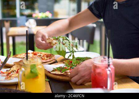 L'heure du repas à la pizzeria, l'homme de prendre une tranche de pizza le coup avec une profondeur de champ très fin Banque D'Images