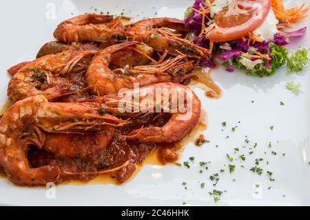 Crevettes cuites dans une sauce tomate et fromage avec cilantro hachée et légumes crus sur une assiette blanche Banque D'Images
