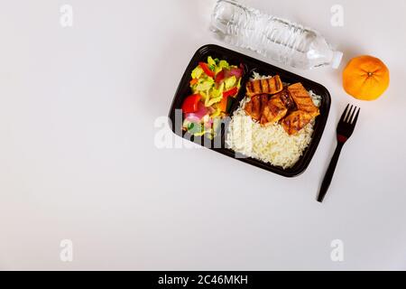 Repas prêt à manger sur un contenant contenant à nourriture avec fourchette, boisson et orange. Banque D'Images