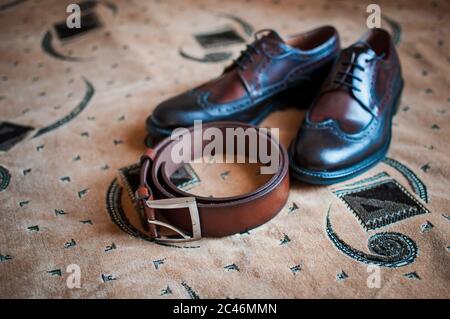 Chaussures Mans et ceinture marron sur le tapis Banque D'Images