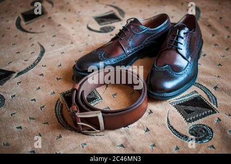 Chaussures Mans et ceinture marron sur le tapis Banque D'Images