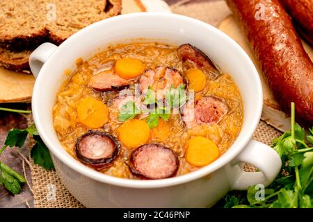 Soupe maison à la choucroute avec carottes et saucisses, plat traditionnel à polir Banque D'Images