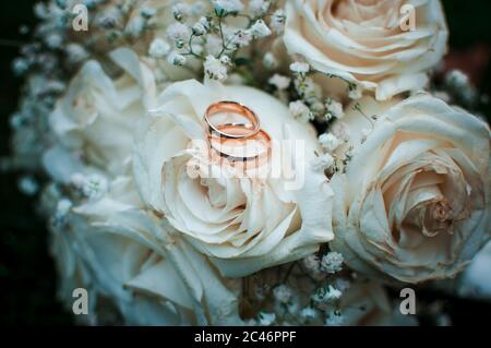 Anneaux de mariage dorés couchés sur le bouquet blanc de fleurs Banque D'Images