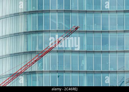 Grue de construction en face d'un bâtiment moderne dans un façade en verre Banque D'Images