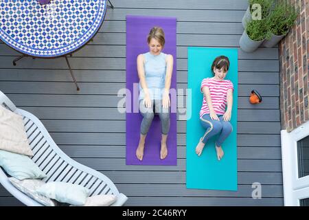 Vue de la tête de la mère et de la fille s'exerçant ensemble à la maison sur le pont Banque D'Images