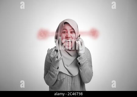 Une jeune femme musulmane asiatique en colère contre un appel téléphonique, criant au téléphone. Gros plan portrait du corps, image monochrome noir et blanc Banque D'Images