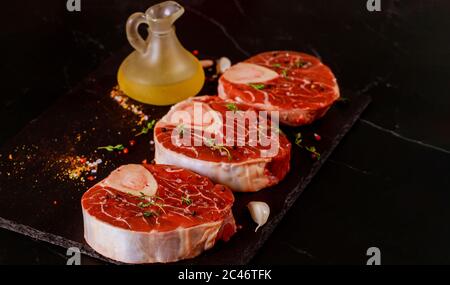 Branche de bœuf coupée avec épices et ail sur panneau noir. Banque D'Images