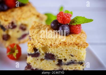 Morceau de gâteau au café aux myrtilles avec baies fraîches sur plaque blanche sur fond blanc. Gros plan. Banque D'Images