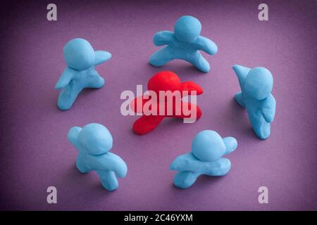 Personnes de plasticité bleue entourant la personne de plasticité rouge. Démarquez-vous de la foule. Le concept d'intimidation. Gros plan. Banque D'Images