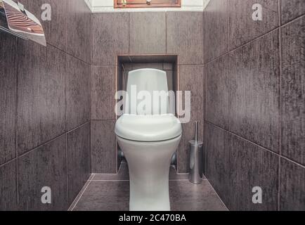 Cuvette de toilette montée en blanc dans la salle de bains moderne avec miroir et brosse de toilette Banque D'Images