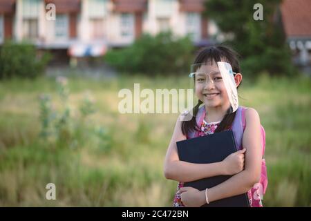 Souriez une petite fille étudiante portant un masque de protection pendant qu'elle retourne à l'école après la quarantaine Covid-19 Banque D'Images