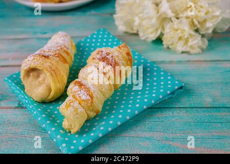 Petits pains de pâte feuilletée farcis à la crème douce et aux fleurs. Banque D'Images