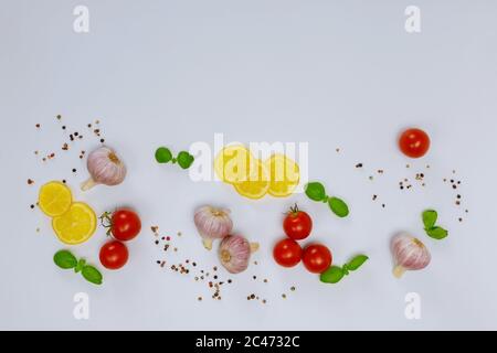 Épice avec citron, ail, tomate et basilic sur fond blanc. Banque D'Images