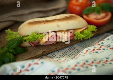 Pain italien, baguette au salami et fromage jaune enveloppés dans du papier Banque D'Images