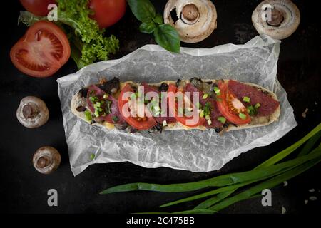 Pain italien, baguette au salami et fromage jaune enveloppés dans du papier Banque D'Images