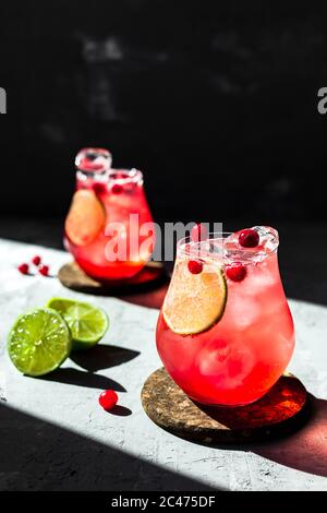 Tonique de canneberges avec citron vert dans de magnifiques verres, fond gris, lumière naturelle directe Banque D'Images