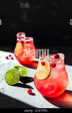 Tonique de canneberges avec citron vert dans de magnifiques verres, fond gris, lumière naturelle directe Banque D'Images