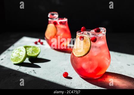 Tonique de canneberge avec chaux dans de magnifiques verres, fond gris, lumière naturelle directe, photo horizontale Banque D'Images