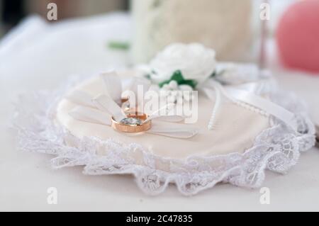 Paire d'anneaux de mariage dorés sur l'oreiller blanc Banque D'Images
