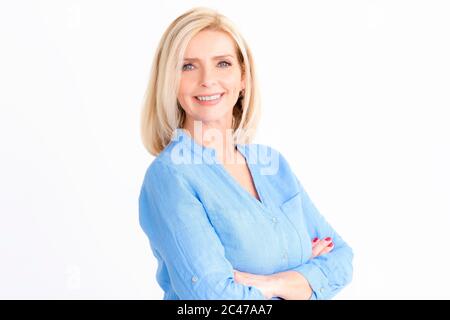 Portrait photo d'une belle femme âgée regardant l'appareil photo et souriant tout en se tenant debout sur un fond blanc isolé. Banque D'Images