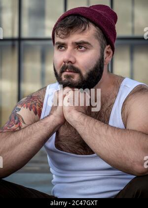 Jeune homme barbu français, avec tatouages, pris à l'extérieur avec la lumière naturelle à Paris, France Banque D'Images