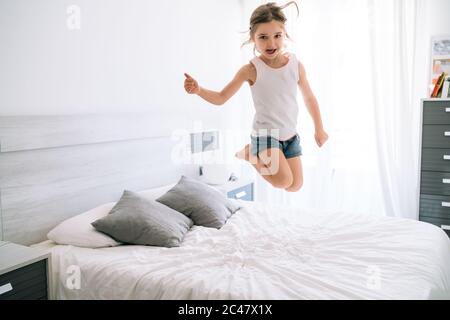 fille sautant sur le lit avec plaisir pendant covid 19 faire ok avec le doigt Banque D'Images