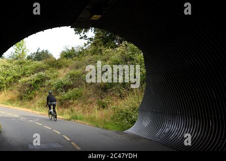 Un cycliste est à vélo depuis un tunnel sur le sentier Galloping Goose Trail, dans la ville de View Royal, dans le grand Victoria. L'ancien chemin de fer est utilisé par les piétons Banque D'Images