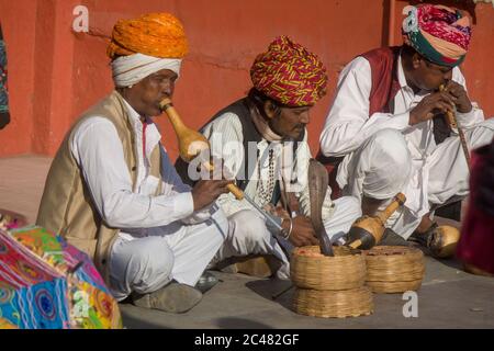 Les charmeurs de serpent jouent et agrègent autour d'un instrument appelé un pungi pour hypnotiser une cobra en Inde Jaipur Banque D'Images