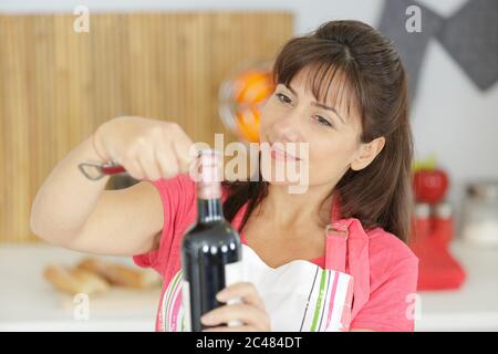 femme essayant d'ouvrir une bouteille de vin Banque D'Images