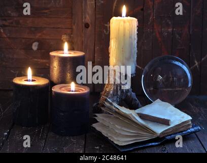 La vie encore et toujours créepy avec des bougies allumées, boule de cristal et journal ouvert sur table de sorcière. Esotérique, wicca et occulte fond avec des objets magiques, la fortune Banque D'Images