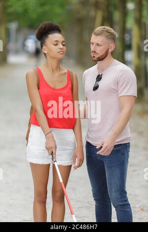 homme assistant femme aveugle avec un bâton blanc dans la rue Banque D'Images
