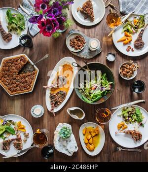 Table moderne de printemps avec agneau, salade de printemps, betteraves dorées, boissons mélangées et tarte aux noix de pécan Banque D'Images