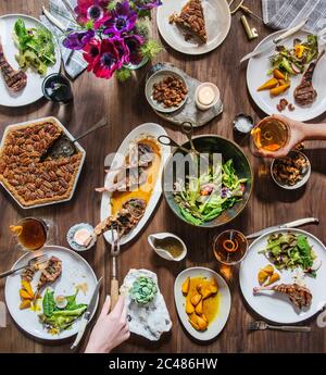 Table moderne de printemps avec agneau, salade de printemps, betteraves dorées, boissons mélangées et tarte aux noix de pécan Banque D'Images