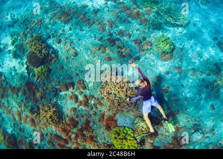 Bonnes vacances en famille. Homme en masque de plongée avec caméra plongée sous-marine avec des poissons tropicaux dans la piscine de corail. Voyage style de vie, sport nautique Banque D'Images