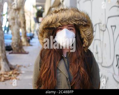 Une jeune fille dans le fond d'une rue vide porte un masque facial qui protège contre la propagation de la maladie de COVID coronavirus gros plan d'une femme Banque D'Images