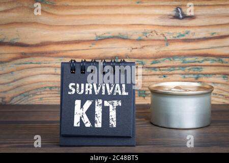 KIT DE SURVIE. Carnet noir et peut sur un fond de texture bois Banque D'Images