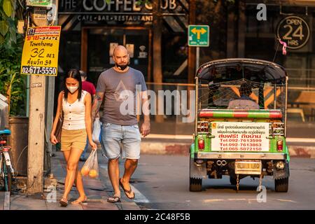 Couple portant un masque facial passant Tuk Tuk dans la rue pendant la pandémie Covid 19, Bangkok, Thaïlande Banque D'Images