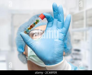 Le médecin tient le tube à essai avec une collection de virus à l'intérieur, se concentrer sur une main, visage flou. Recherche d'un micro-organisme dangereux. Banque D'Images