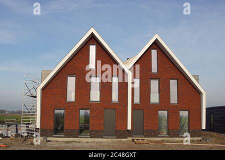 Maisons neuves et modernes construites le long de la prairie aux pays-Bas. Novembre, près du village hollandais de Bergen. Banque D'Images