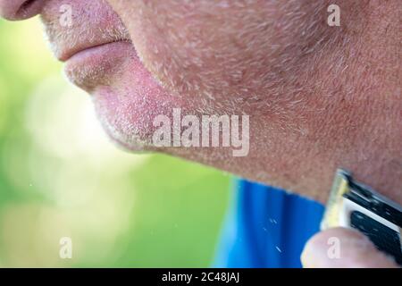 Un homme coupe sa barbe blanche avec une tondeuse Banque D'Images