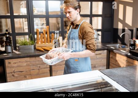 Portrait d'un beau vendeur travaillant avec de la crème glacée au comptoir de pâtisserie ou de café Banque D'Images