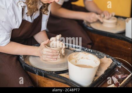 La fabrication de céramiques. Deux femmes préparent l'argile pour le travail sur la roue de poterie. Vue rapprochée des mains. Banque D'Images