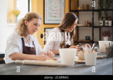 Femmes travaillant dans un studio de poterie, souriant et parlant. Atelier de céramique, cours de maître en poterie. Banque D'Images