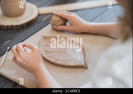 Femme décorant une plaque de poterie artisanale en gros plan Banque D'Images