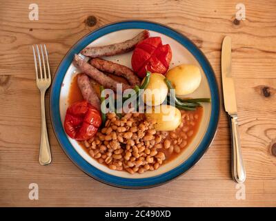 Déjeuner plat principal saucisses avec haricots verts pommes de terre nouvelles, haricots italiens tomates grillées et sauce plaque blanche bord bleu plateau en bois et cu Banque D'Images