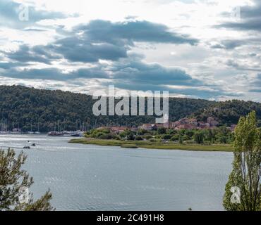 Ville de Skradin vue d'une route proche en montée. Rivière Krka qui coule autour de la petite ville, clocher qui s'élève au-dessus de la colline Banque D'Images